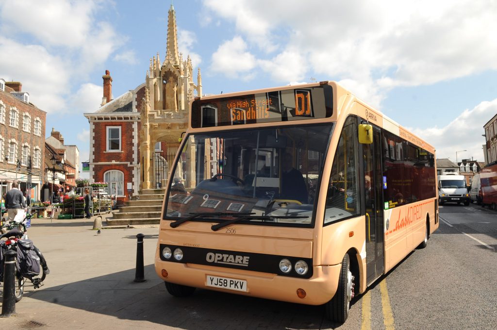 The yellow dash direct bus parked in front of the Market Cross in Leighton Buzzard town centre
